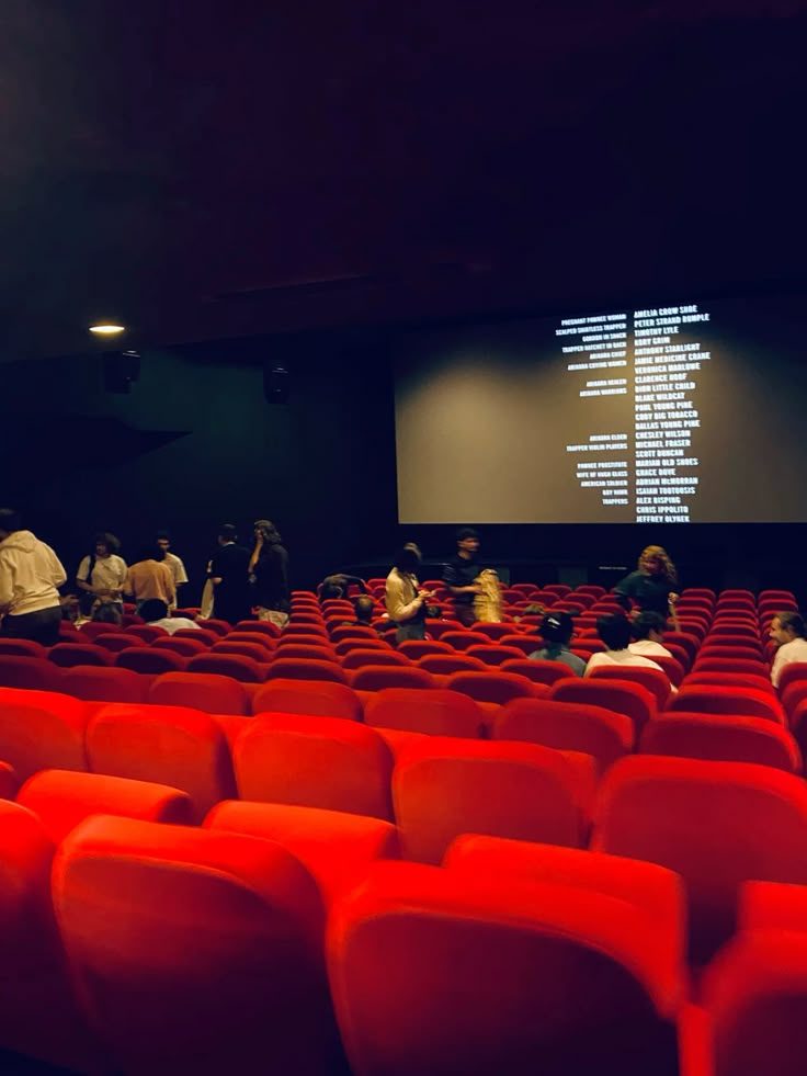 Sala de cinema com poltronas vermelhas e público após a sessão